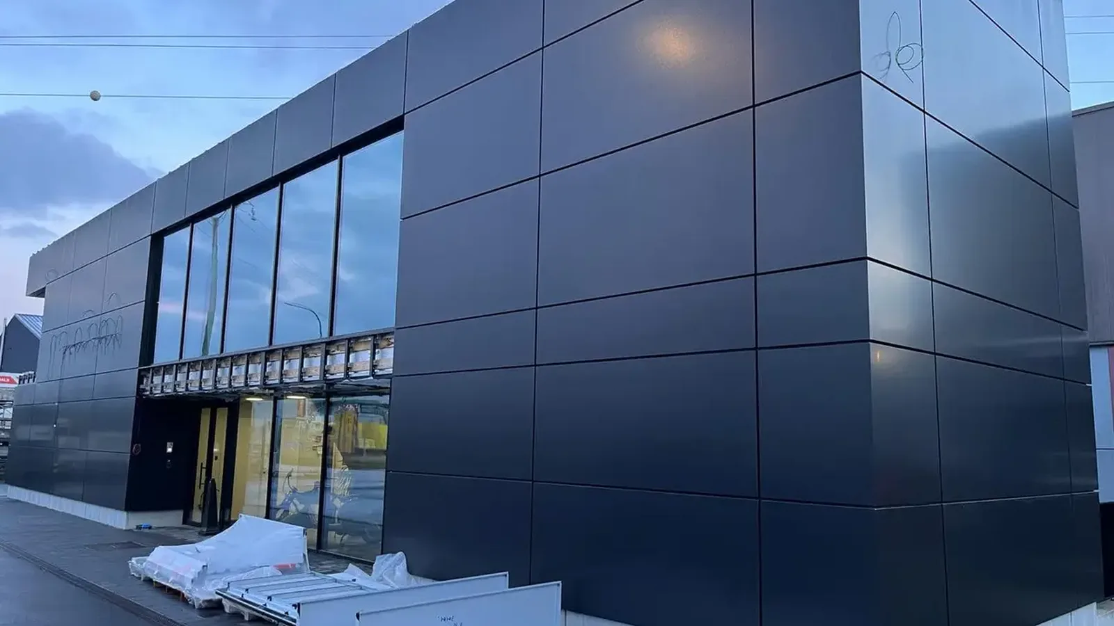 Bâtiment contemporain habillé de grands panneaux d'aluminium anthracite, avec une large baie vitrée au rez-de-chaussée