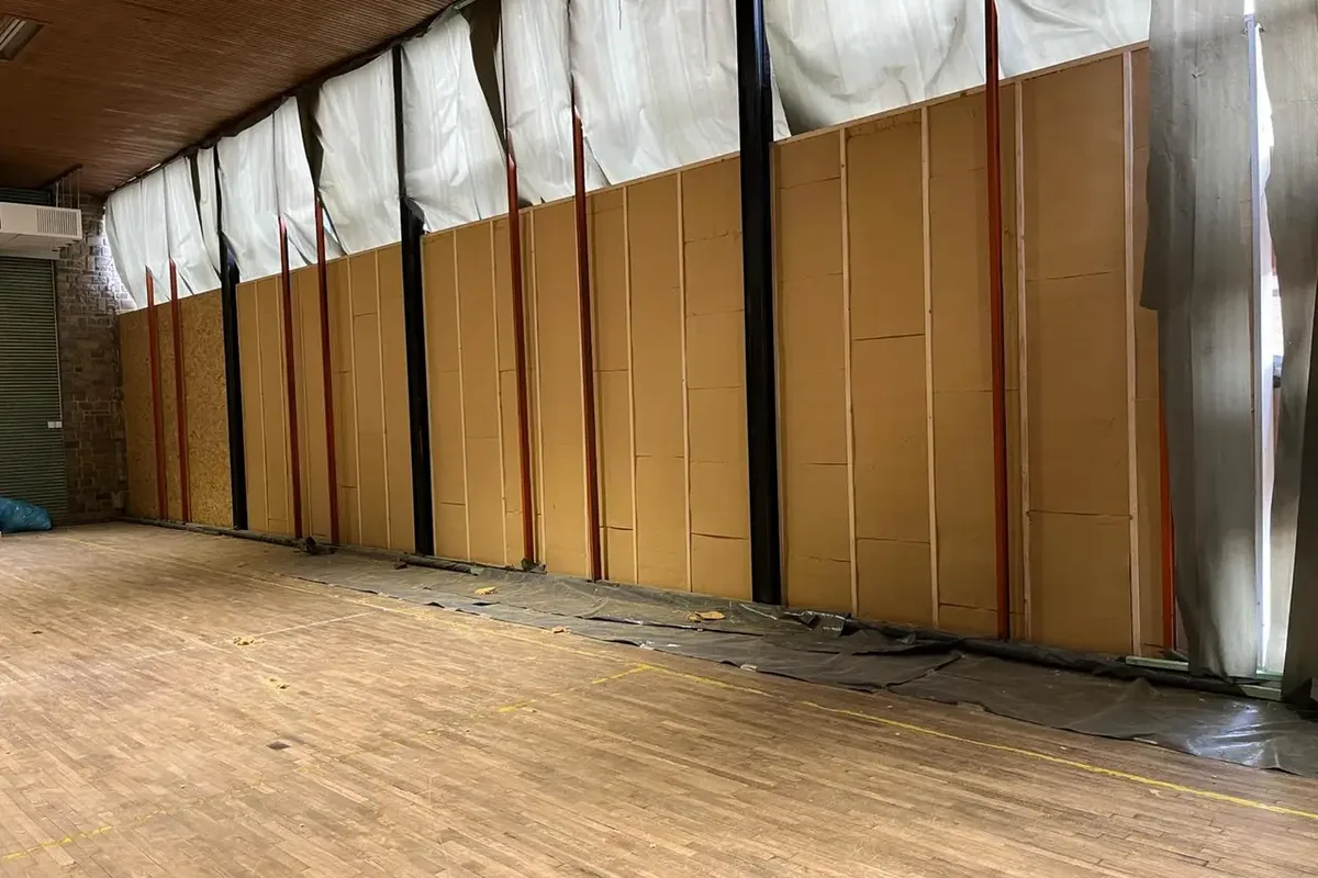 Grande surface de panneaux isolants posés sur un mur, bâche et plancher de chantier