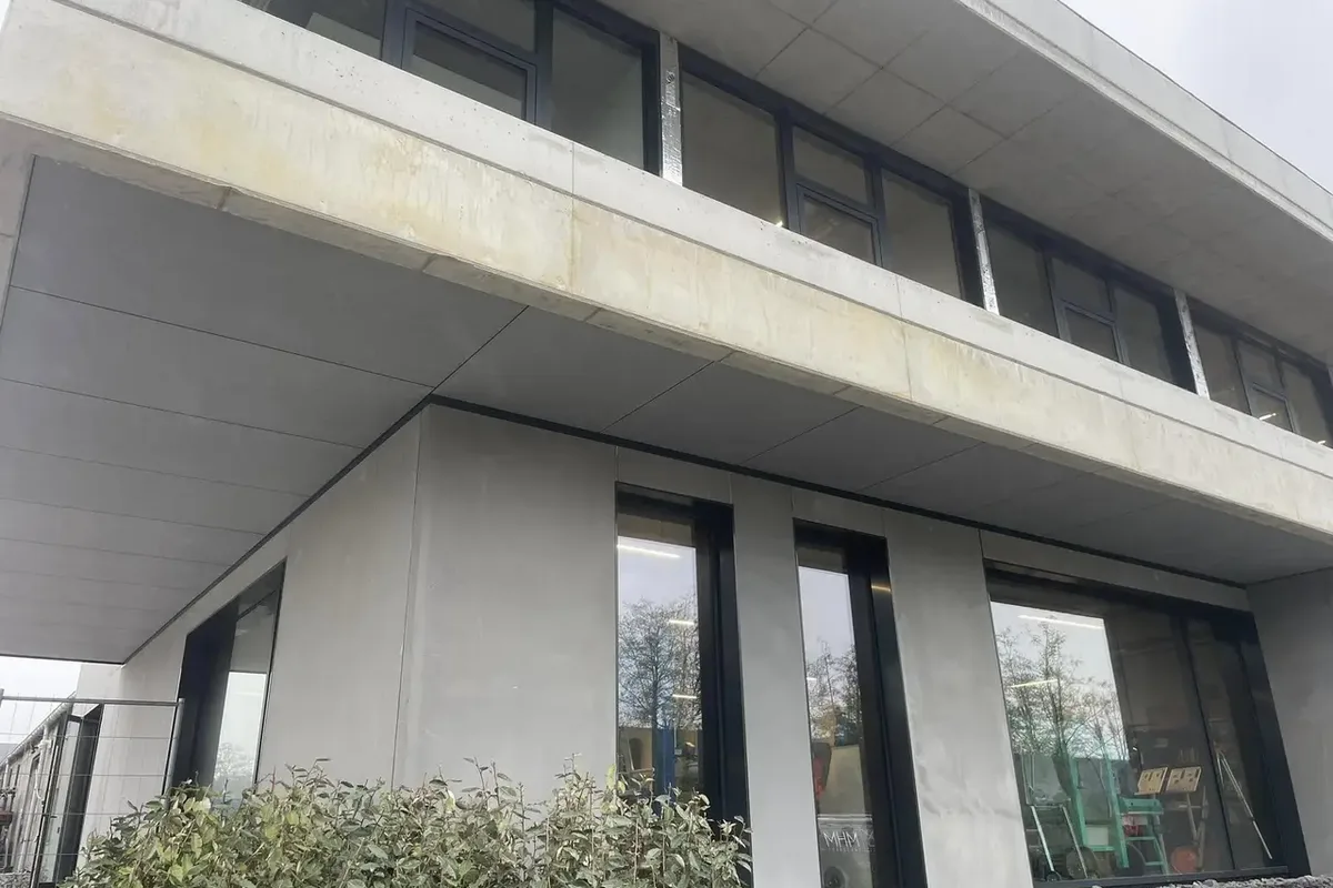 Façade enduite et panneaux clairs au-dessus de grandes baies vitrées