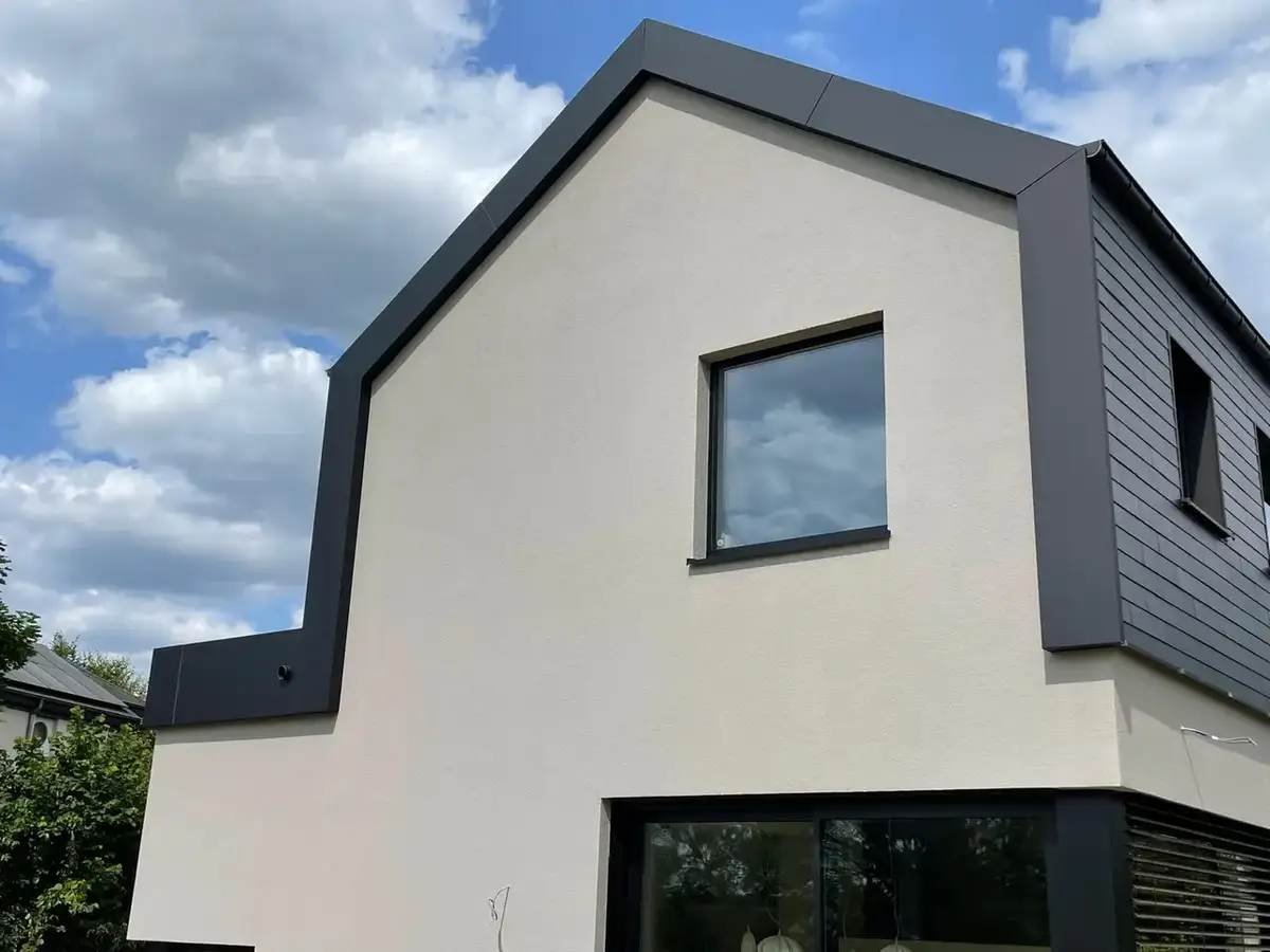 Maison à pignon : façade enduite beige, bardage anthracite en rive de toiture et grande baie vitrée